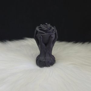 Bougie décorative noire en forme de rose entourée de deux mains montantes