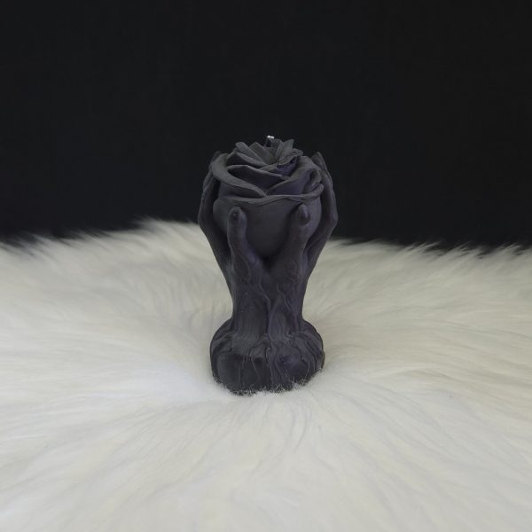 Bougie décorative noire en forme de rose entourée de deux mains montantes