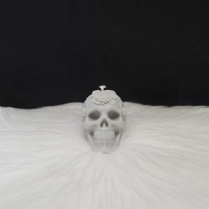 Bougie décorative grise en forme de crâne avec fleurs incrustées sur le dessus