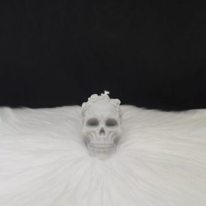 Bougie décorative grise en forme de crâne avec fleurs incrustées sur le dessus