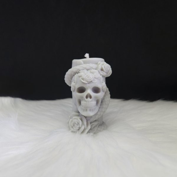 Bougie décorative grise en forme de cylindre avec crâne, serpent enroulé et roses sculptées