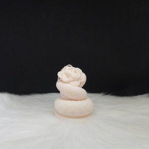 Bougie décorative couleur crème en forme de rose entourée d’un serpent enroulé