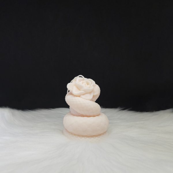 Bougie décorative couleur crème en forme de rose entourée d’un serpent enroulé