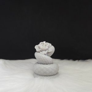 Bougie décorative grise en forme de rose entourée d’un serpent enroulé