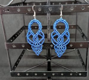 Boucle d'oreilles en macramé marron qui forment des arabesques fluides et harmonieuses.