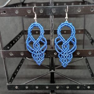 Boucle d'oreilles en macramé marron qui forment des arabesques fluides et harmonieuses.