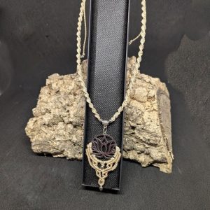 Le pendentif fleur de lotus acier inoxydable argenté et le tour de cou sont réalisés en macramé beige solaire, le tout monté sur une lanière torsadée, dont la longueur est ajustable grâce à son système de nœud coulissant.